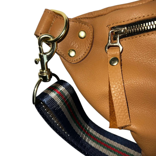 Close-up of The Joan Saddle Bag featuring gold hardware and a striped adjustable strap, showcasing quality and beauty.
