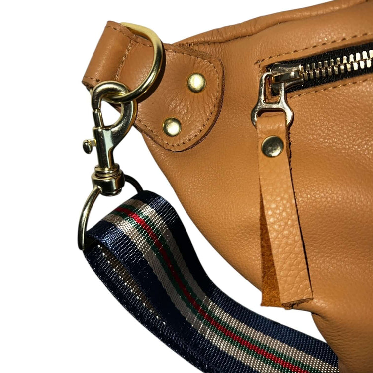 Close-up of The Joan Saddle Bag featuring gold hardware and a striped adjustable strap, showcasing quality and beauty.